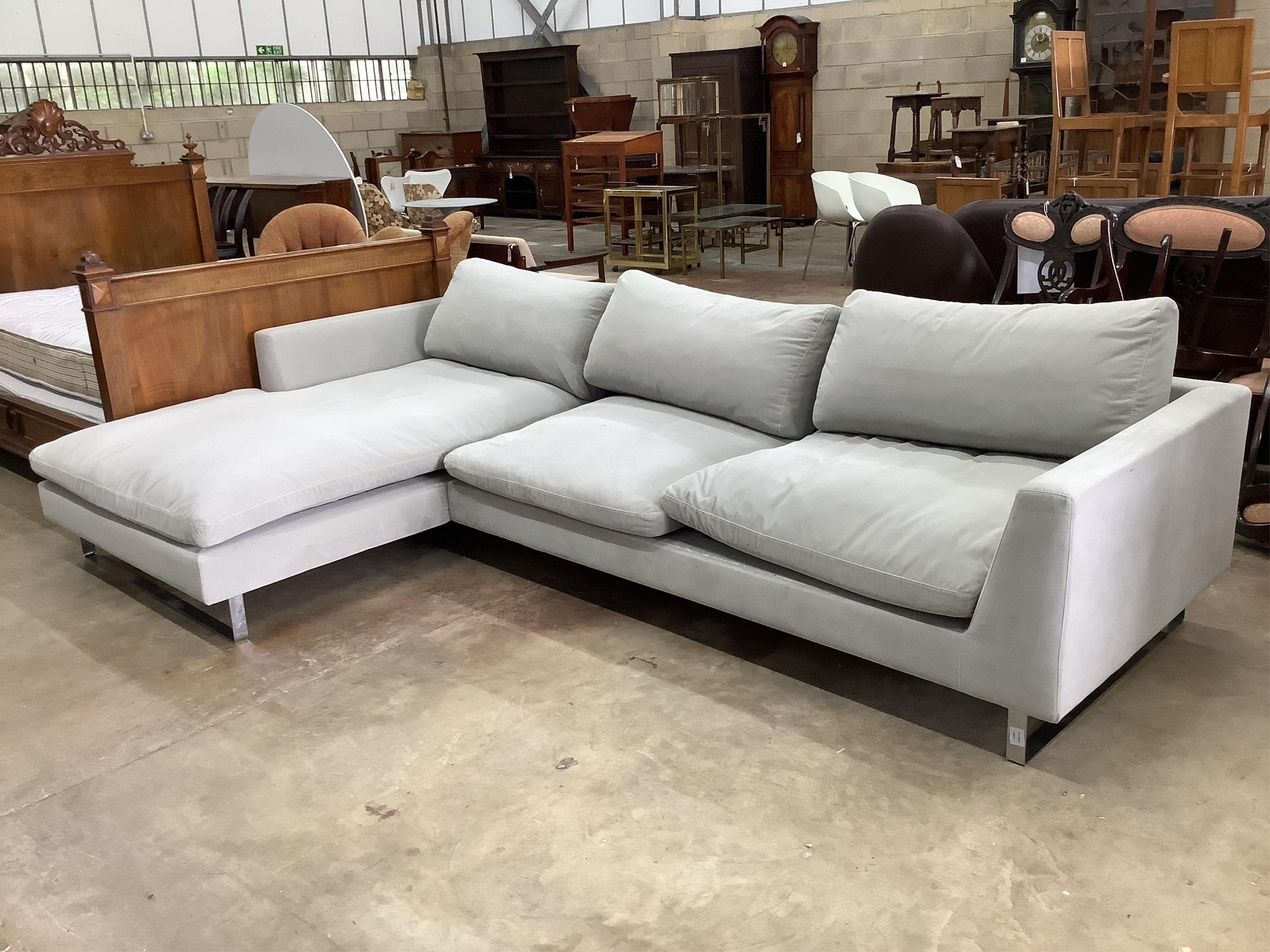 A pale grey fabric upholstered L shaped settee with chromed feet, width 304cm, height 190cm. Condition - fair